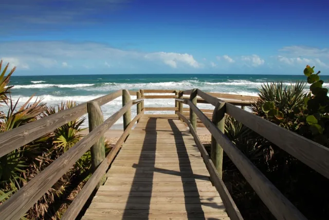 A wooden dune walkover with railings leading to the ocean beach