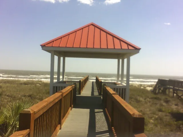 A dune walkway leading to a gazebo with a red metal roof overlooking the ocean
