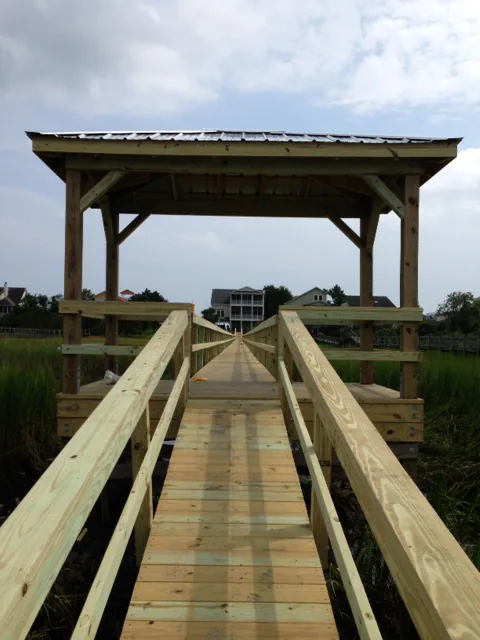 A railed walkway leading into a covered dock with a metal roof