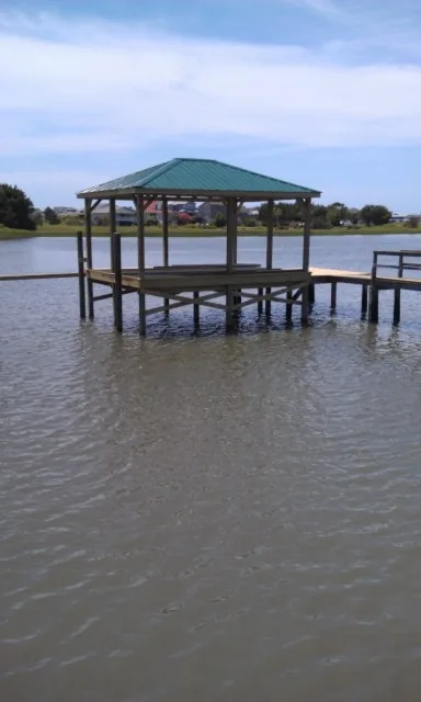A covered dock with a green metal roof standing over open coastal water