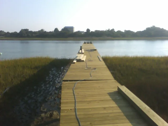 New pier decking being installed across marsh grass toward open water