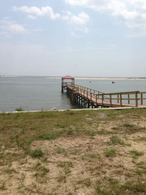 A long pier reaching out over open water to a covered platform with a red roof